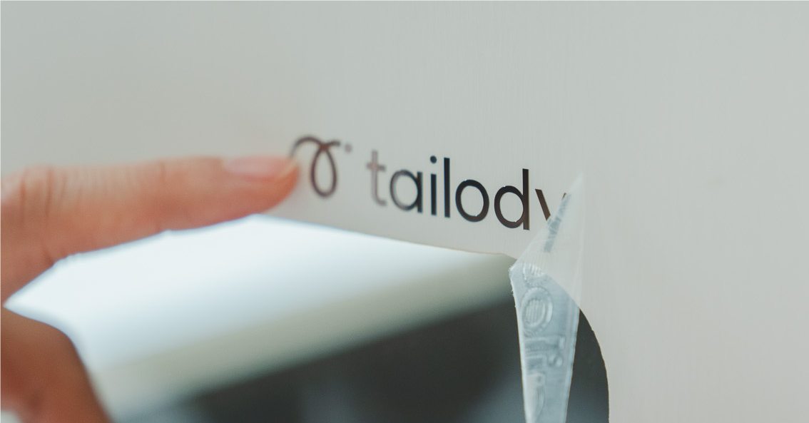 A hand placing the Tailody logo on a Mute house panel